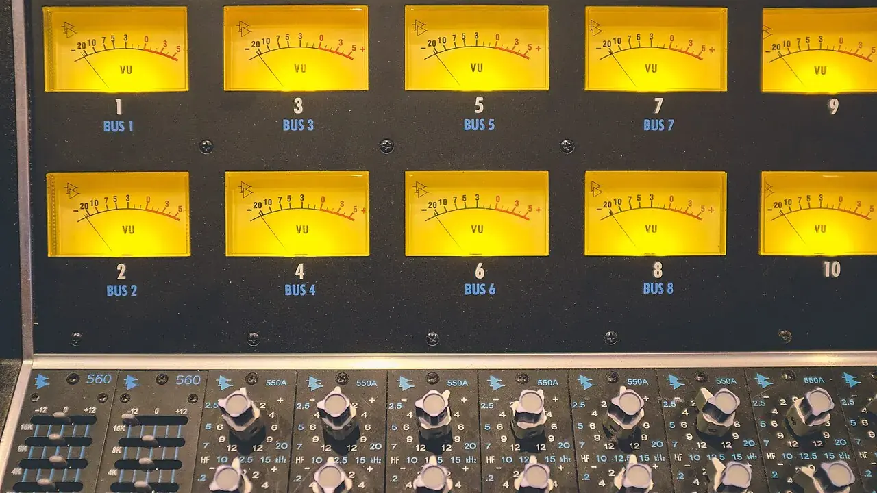 Two rows of illuminated yellow VU meters on a recording console, above rows of equaliser knobs