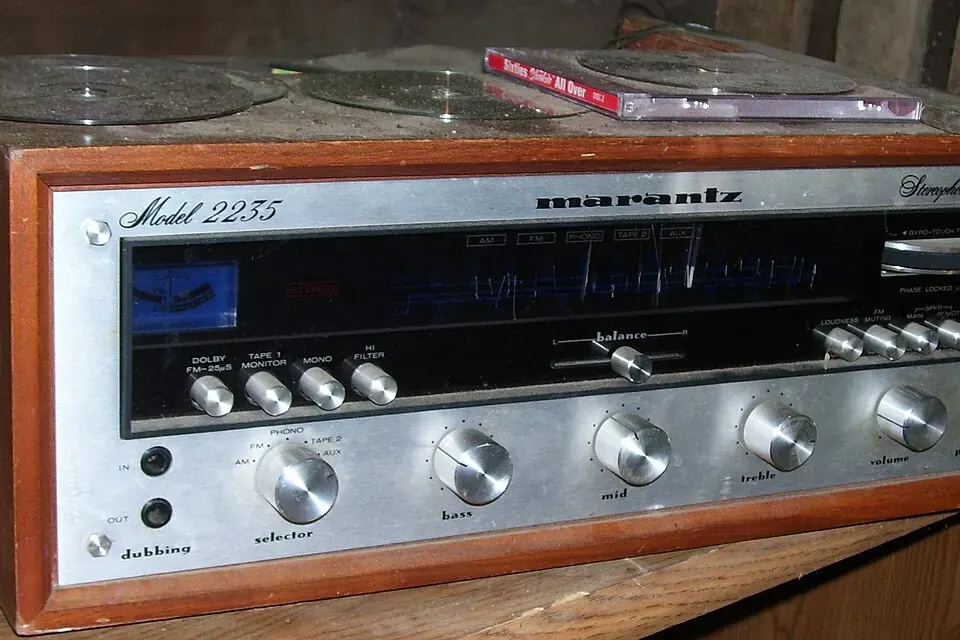 The silver front panel of a 1970s stereo receiver with a long tuning dial, signal meter and rows of knobs