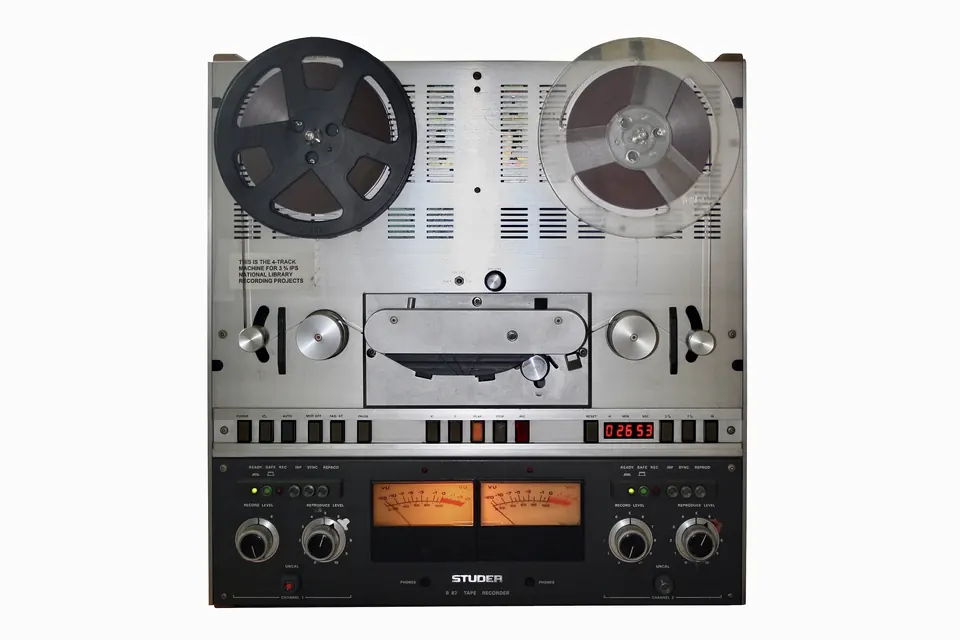 Front of a professional Studer B67 open-reel tape recorder with two reels mounted and VU meters below the transport